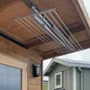 A ceiling-mounted clothes drying rack is shown installed under a wooden overhang, with a portion of a house visible in the background. Podgląd zdjęcia produktu