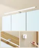 A collage showing a modern light fixture above a mirrored cabinet, close-ups of the fixture's mounting hardware, and an electrical plug connecting to a wall outlet. Náhled obrázku produktu