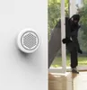 A burglar is breaking into a house through a window, while a smart alarm siren is mounted on the wall. Produktbild-Vorschau