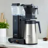 A black and silver Moccamaster coffee maker with a thermal carafe sits on a kitchen counter. Produktbild-Vorschau