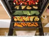 An open oven with multiple racks filled with various foods being prepared. Produktbild-Vorschau
