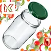 A glass jar with a green lid, surrounded by various fresh vegetables and herbs. Podgląd zdjęcia produktu