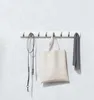 A white flip hook rack mounted on a textured light gray wall, holding a dog leash, a canvas tote bag, and a gray scarf. Podgląd zdjęcia produktu