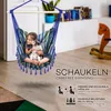 A young girl and her dog are sitting in a colorful hanging chair in a room. Náhľad obrázku produktu