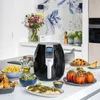 A kitchen counter with a black air fryer and various food items, including chicken, fries, salad, stuffed peppers, and cake. Produktbild-Vorschau