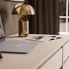 A desk with a laptop, a magazine, and a golden lamp. Produktbild-Vorschau