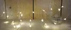 A string of LED lights coiled around a spool, set against a wooden background. Produktbild-Vorschau