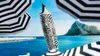 A highlighter with a zebra pattern is placed in the foreground, with beach umbrellas and a mountain in the background. Voir les images du produit