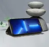 A smartphone in a wallet case is displayed on a surface, with stacked stones and a plant in the background. Produktbild-Vorschau