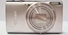 A silver Canon Ixus 285 compact camera is shown from the front against a white background. Produktbild-Vorschau