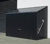 A dark gray metal storage box with a sloped roof, positioned outdoors next to a white wall and a building with horizontal gray siding. Náhľad obrázku produktu