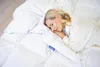 A woman is sleeping peacefully on a bed with a white duvet. Produktbild-Vorschau