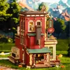 A miniature wooden model of a building, possibly a shop or factory, set in an outdoor environment with blurred trees and buildings in the background. Podgląd zdjęcia produktu