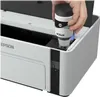 A hand is shown pouring ink from a bottle into an Epson printer. Náhľad obrázku produktu