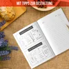 An open cookbook with illustrations and text, placed on a burlap-like surface with some bread and lavender sprigs. Produktbild-Vorschau