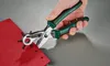 A hand is using a hole punch tool to make holes in a red piece of material. Produktbild-Vorschau