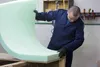 A man in a blue uniform is holding a large piece of light green foam. Produktbild-Vorschau