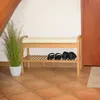 A shoe rack with a bench and shoes on the lower shelf, next to a potted plant and a door. Produktbild-Vorschau