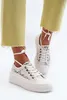 A person wearing white lace sneakers with yellow pants. Voir les images du produit