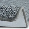 A close-up view of the corner of a gray carpet, showing its texture and binding. Produktbild-Vorschau