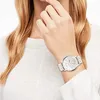 A woman wearing a white sweater and a watch on her wrist. Produktbild-Vorschau