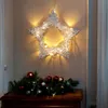 A star-shaped light decoration hangs above a festive arrangement of pine branches and Christmas ornaments on a wooden surface. Anteprima dell’immagine prodotto