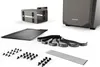 A collection of computer case accessories, including a mounting bracket, a flat panel, cable ties, and screws, arranged on a white background. Produktbild-Vorschau