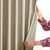 Hands holding a beige curtain, revealing a white background. Produktbild-Vorschau