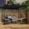 Three people are sitting on sofas under a black pergola in a backyard setting at dusk. Náhled obrázku produktu