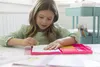 A young girl is drawing and coloring at a table. Anteprima dell’immagine prodotto