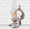 A vintage-style oil lamp with a mirror attachment is displayed against a white brick wall. Podgląd zdjęcia produktu