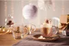 A festive scene with hot chocolate and mugs, decorated with lights and ornaments. Produktbild-Vorschau
