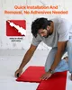A man is kneeling on the floor, assembling red interlocking tiles. Podgląd zdjęcia produktu