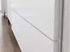 A close-up view of a white cabinet with a subtle groove indicating a drawer or door opening, set against a light wooden floor. Náhľad obrázku produktu