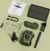 A flat lay of a trail camera kit, including the camera, solar panel, manual, cables, and mounting accessories, arranged on a light green background. Produktbild-Vorschau