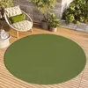 A round green rug on a wooden deck with a chair and plants. Voir les images du produit