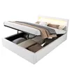 A white bed with storage is shown with the storage compartment open and filled with bedding. The headboard has LED lighting. Náhled obrázku produktu