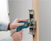 A person is using a router jig to drill holes in a wooden door frame. Voir les images du produit