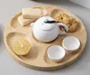 A wooden serving tray with compartments holding a teapot, cups, cookies, wafers, and a lemon slice. Voir les images du produit