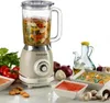 A retro-style blender filled with ingredients, surrounded by fresh vegetables, oil, and bowls of soup. Produktbild-Vorschau