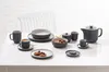 A table set with a grey coffee and dinnerware set, including cups, saucers, bowls, plates, and a teapot. Produktbild-Vorschau
