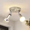 A close-up view of a modern, two-bulb ceiling light fixture made of brushed metal, mounted on a white ceiling. Produktbild-Vorschau