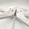 A close-up view of a white paper star lantern with cut-out star shapes and dots, showing the internal structure and a white string hanging down. Produktbild-Vorschau