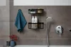 A bathroom shelf with toiletries and a towel hanging on the wall. Produktbild-Vorschau