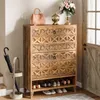 A wooden shoe cabinet with two drawers and open shelves is shown in an entryway, next to an umbrella stand and a door. Podgląd zdjęcia produktu