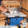 A person is using a table saw to cut a piece of wood. The saw is blue and silver, with a clear safety guard. Produktbild-Vorschau