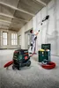 A man is sanding a wall in a room under renovation, with a vacuum cleaner and a toolbox nearby. Náhľad obrázku produktu
