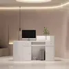 A modern white reception desk with a computer and decorative plant. Produktbild-Vorschau