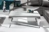 A modern living room setting with a marble-look coffee table in the foreground and a grey sectional sofa in the background. Náhled obrázku produktu