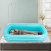 An elderly man is lying in a blue inflatable bathtub placed on a mattress in a bedroom. Náhled obrázku produktu